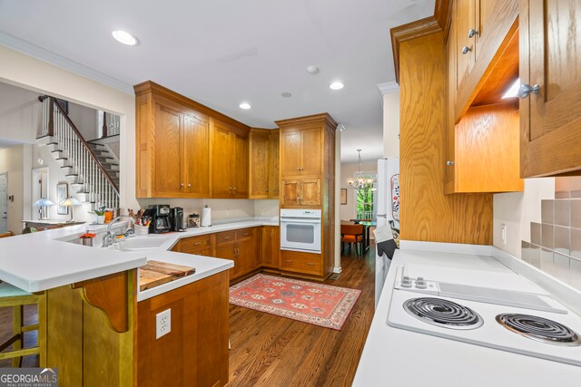 127 Chestnut Ln, Athens, GA 30606 - kitchen featuring white appliances, dark wood finished floors, a peninsula, brown cabinets, and light countertops