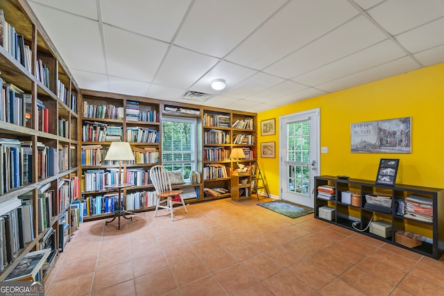 127 Chestnut Ln, Athens, GA 30606 - living area featuring wall of books, a drop ceiling, built in features, tile patterned floors, and healthy amount of natural light