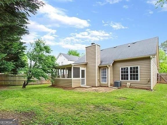 rear view of property featuring central AC unit, a sunroom, and a chimney