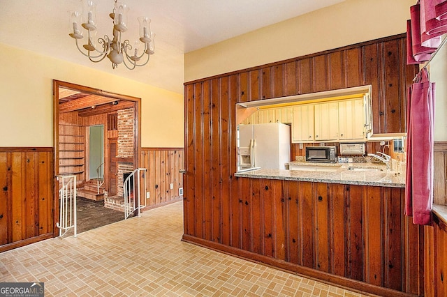 894 Nottingham Dr, Avondale Estates, GA 30002 - kitchen with white fridge with ice dispenser, black microwave, wooden walls, wainscoting, and a chandelier