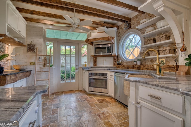 kitchen featuring stainless steel appliances, white cabinetry, light stone countertops, a ceiling fan, and stone tile floors
