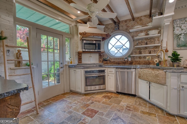 kitchen with stainless steel appliances, open shelves, stone tile floors, beam ceiling, and a ceiling fan