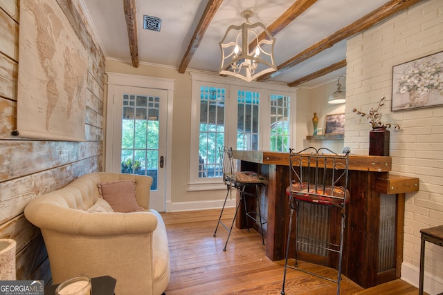 indoor dry bar with wood finished floors, beam ceiling, ornamental molding, a chandelier, and baseboards