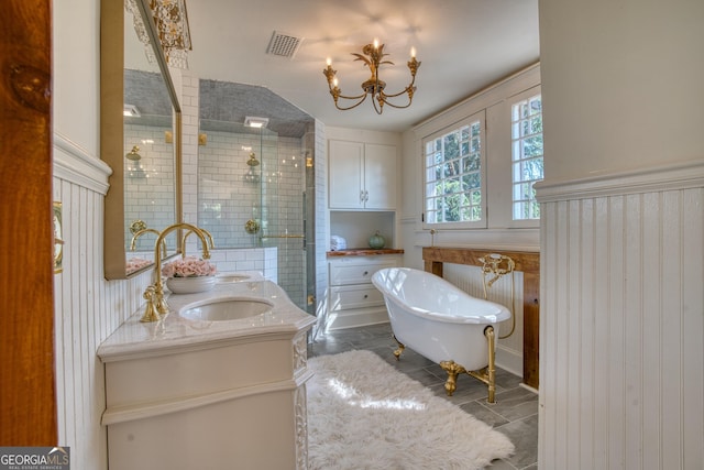 full bathroom featuring a stall shower, double vanity, a soaking tub, and a chandelier