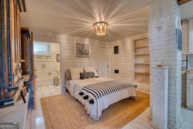 bedroom with crown molding, wooden walls, connected bathroom, and a chandelier