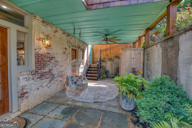 view of patio with a ceiling fan, stairway, and fence