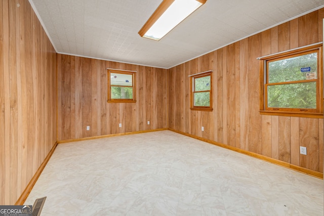 unfurnished room with plenty of natural light, tile patterned floors, wooden walls, and baseboards