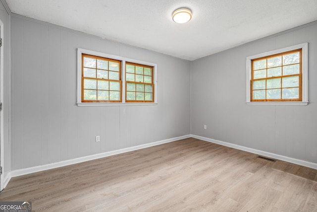 unfurnished room featuring light wood-type flooring, baseboards, and crown molding