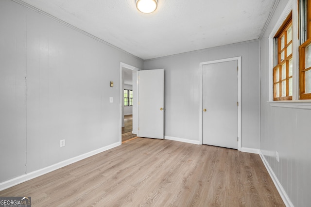 unfurnished bedroom featuring wood finished floors, ornamental molding, and baseboards