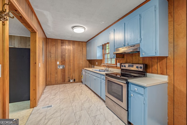 kitchen with electric range, under cabinet range hood, blue cabinetry, a sink, and wooden walls