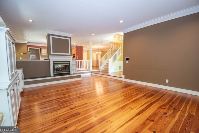 24 Overbrook Ct, Newnan, GA 30263 - unfurnished living room with crown molding, light wood-type flooring, a chandelier, a glass covered fireplace, and recessed lighting