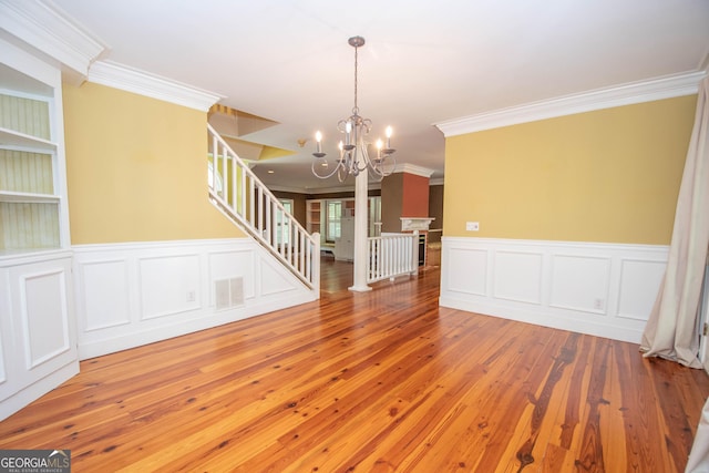 24 Overbrook Ct, Newnan, GA 30263 - unfurnished living room featuring ornamental molding, a chandelier, wood-type flooring, stairway, and a wainscoted wall