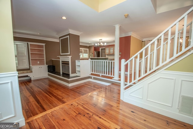 24 Overbrook Ct, Newnan, GA 30263 - unfurnished living room with crown molding, wood finished floors, a decorative wall, a multi sided fireplace, and a chandelier
