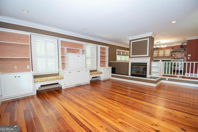 24 Overbrook Ct, Newnan, GA 30263 - unfurnished living room featuring light wood-style floors, ornamental molding, a chandelier, a glass covered fireplace, and recessed lighting