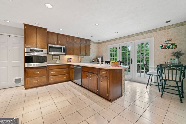 1260 Willeo Creek Dr, Roswell, GA 30075 - kitchen featuring stainless steel appliances, a peninsula, light countertops, light tile patterned flooring, and wallpapered walls