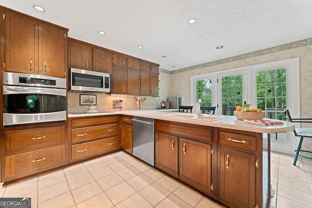 1260 Willeo Creek Dr, Roswell, GA 30075 - kitchen featuring stainless steel appliances, a peninsula, wallpapered walls, light countertops, and light tile patterned floors