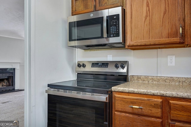27 Pocahontas Rd, Midway, GA 31320 - kitchen with stainless steel appliances, brown cabinets, light countertops, and carpet flooring