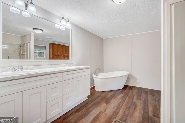 27 Pocahontas Rd, Midway, GA 31320 - bathroom featuring a shower, a textured ceiling, double vanity, wood finished floors, and a soaking tub