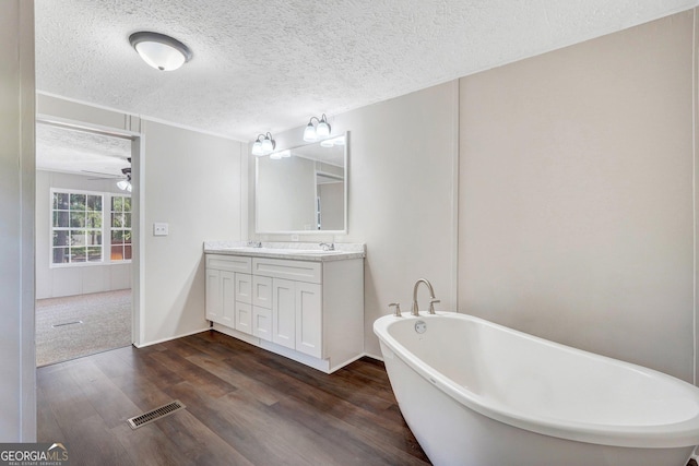 27 Pocahontas Rd, Midway, GA 31320 - bathroom featuring wood finished floors, vanity, a textured ceiling, a freestanding tub, and a ceiling fan