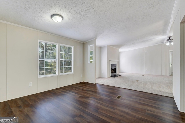27 Pocahontas Rd, Midway, GA 31320 - unfurnished living room with wood finished floors, a fireplace with raised hearth, ornamental molding, a ceiling fan, and a decorative wall