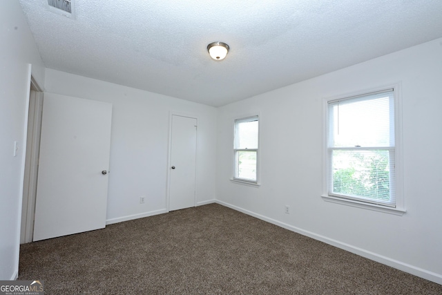 1309 Newton Rd, Albany, GA 31701 - unfurnished bedroom with dark carpet, baseboards, a textured ceiling, and a closet
