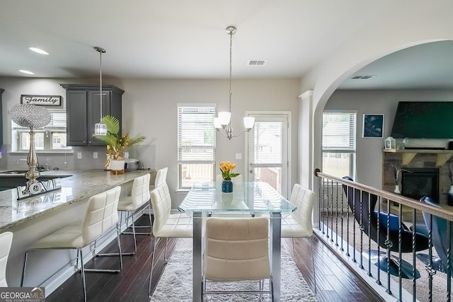 dining room featuring dark wood-style floors, arched walkways, healthy amount of natural light, and recessed lighting
