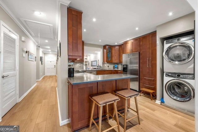 1141 Moorestown Cir, Decatur, GA 30033 - kitchen featuring appliances with stainless steel finishes, stacked washer / dryer, a peninsula, light wood-style flooring, and recessed lighting