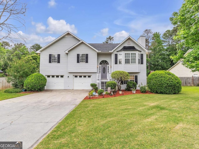 raised ranch with a chimney, a garage, and driveway