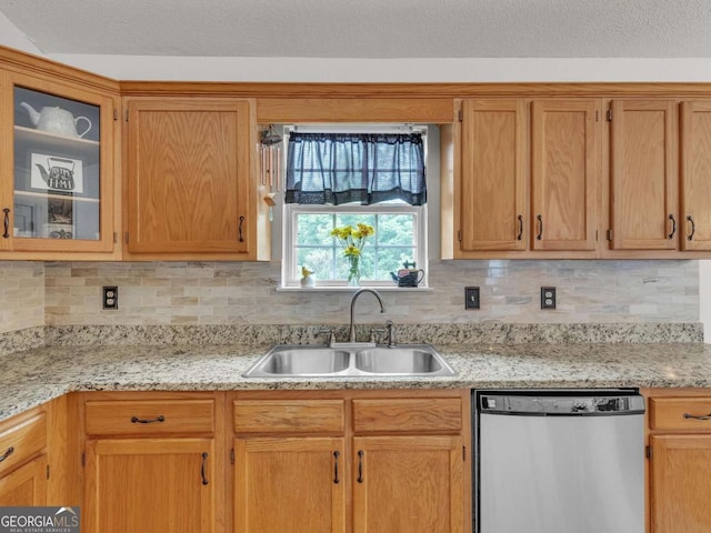 kitchen featuring stainless steel dishwasher, a sink, backsplash, and glass insert cabinets