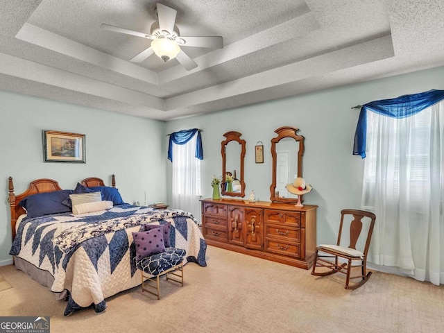 carpeted bedroom featuring a tray ceiling, a textured ceiling, and ceiling fan