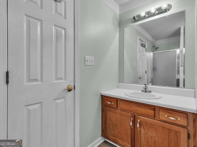 bathroom with vanity, a shower with door, and crown molding