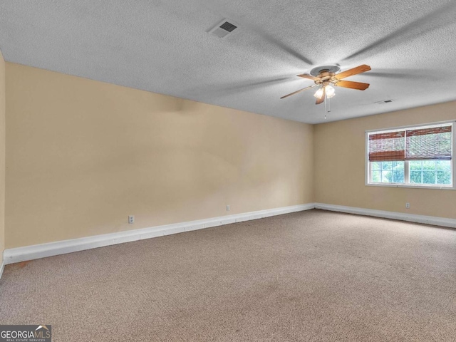 carpeted empty room with a ceiling fan, baseboards, and a textured ceiling