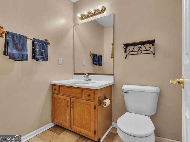 half bath with toilet, vanity, and baseboards