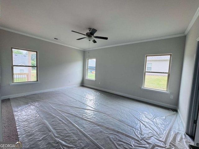 spare room with baseboards, crown molding, and a ceiling fan