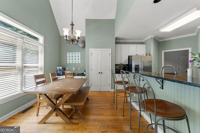 1377 Downington Ln NW, Acworth, GA 30101 - dining room featuring light wood finished floors, a chandelier, crown molding, and a towering ceiling