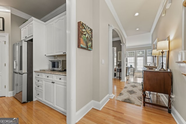 4298 Kingston Gate Cv, Chamblee, GA 30341 - corridor featuring ornate columns, light wood finished floors, arched walkways, crown molding, and baseboards