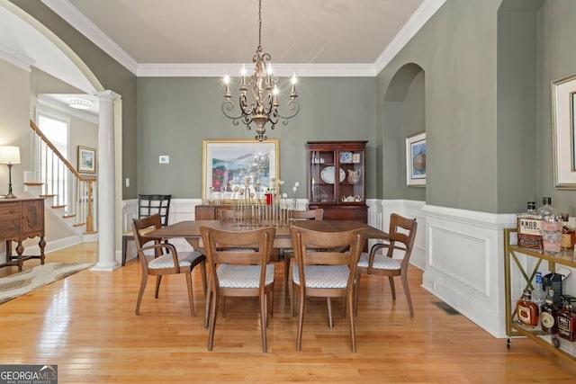 4298 Kingston Gate Cv, Chamblee, GA 30341 - dining space with arched walkways, light wood-style floors, crown molding, stairway, and a wainscoted wall