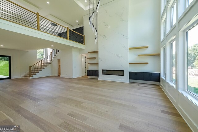 972 Auburn Rd, Dacula, GA 30019 - unfurnished living room with a high ceiling, light wood-style flooring, stairs, a fireplace, and baseboards