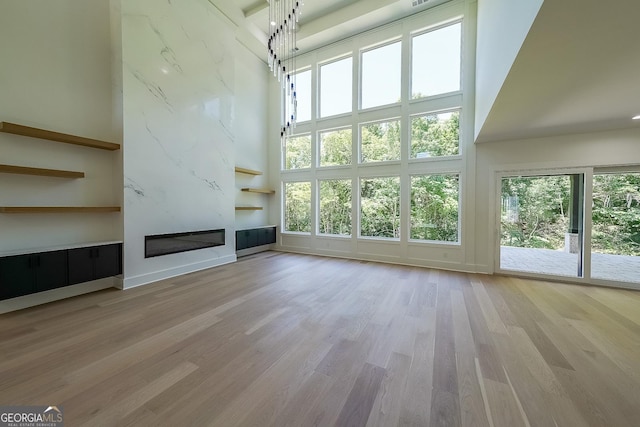 972 Auburn Rd, Dacula, GA 30019 - unfurnished living room with a towering ceiling, plenty of natural light, a fireplace, and wood finished floors