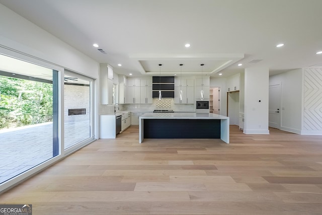 972 Auburn Rd, Dacula, GA 30019 - kitchen featuring a raised ceiling, light countertops, light wood-type flooring, decorative backsplash, and recessed lighting