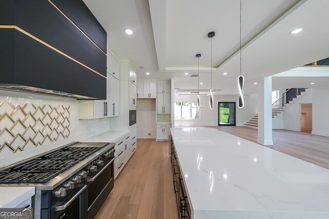 972 Auburn Rd, Dacula, GA 30019 - kitchen with double oven range, range hood, light wood-style flooring, a tray ceiling, and open floor plan