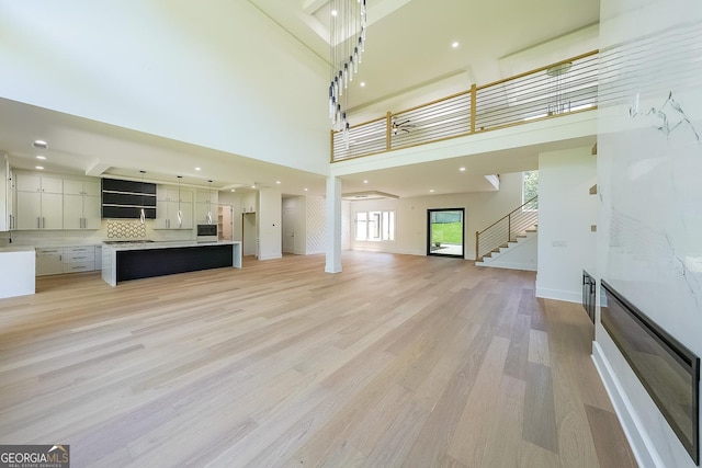 972 Auburn Rd, Dacula, GA 30019 - unfurnished living room featuring a towering ceiling, stairs, light wood finished floors, and recessed lighting