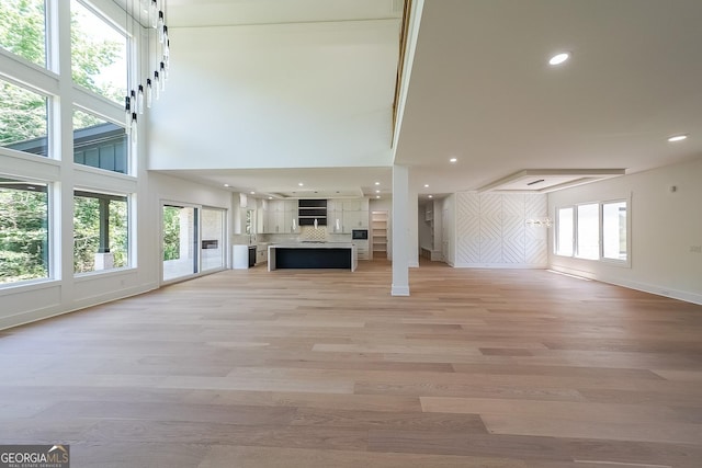 972 Auburn Rd, Dacula, GA 30019 - unfurnished living room with baseboards, light wood finished floors, plenty of natural light, a towering ceiling, and recessed lighting