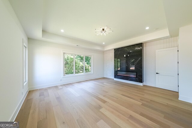 972 Auburn Rd, Dacula, GA 30019 - unfurnished living room featuring light wood-style floors, baseboards, a high end fireplace, recessed lighting, and a tray ceiling