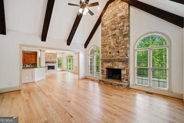 unfurnished living room featuring a fireplace, high vaulted ceiling, beam ceiling, a ceiling fan, and light wood-style floors