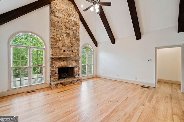 unfurnished living room with beamed ceiling, high vaulted ceiling, a ceiling fan, wood finished floors, and a fireplace