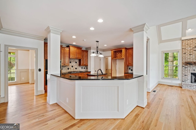 kitchen featuring light wood-type flooring, dark stone counters, tasteful backsplash, gas cooktop, and crown molding
