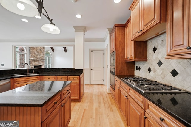 kitchen featuring a sink, stainless steel gas stovetop, oven, crown molding, and light wood-type flooring