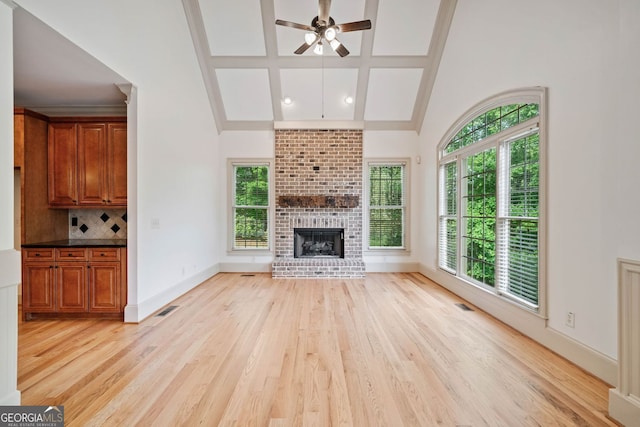 unfurnished living room featuring light wood-style flooring, ceiling fan, a fireplace, baseboards, and beam ceiling