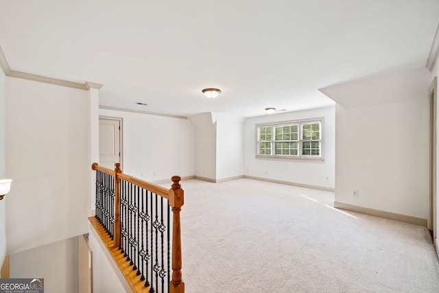 empty room with light colored carpet, baseboards, and crown molding